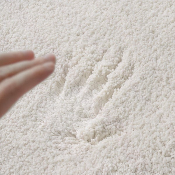 Nahaufnahme eines hellen, flauschigen Teppichs mit Handabdruck