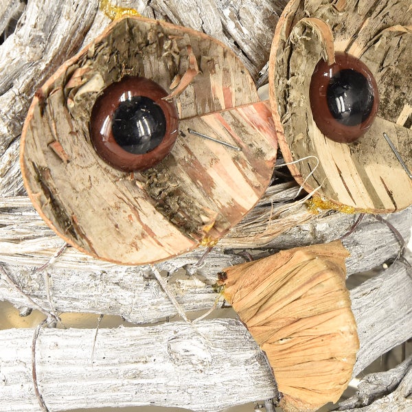 Detailaufnahme einer dekorativen Eule aus natürlichen Materialien wie Holz und Rinde.