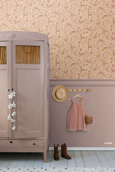 Kinderschlafzimmer mit Vliestapete mit Waldmuster, bemalter Holzschrank, Garderobe mit Sommerkleid und Strohhut sowie Cowboystiefeln auf dem Boden.