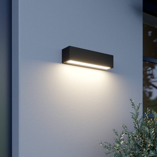 Moderne rechteckige LED-Außenwandleuchte aus dunklem Metall mit warmweißem Licht nach unten an einer hellen Außenwand montiert.