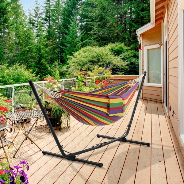 Gestreifte Hängematte mit schwarzem Metallgestell auf einer Holzterrasse vor einem Haus.