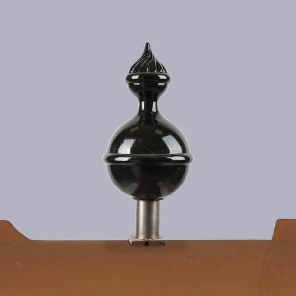 Schwarzer dekorativer Zaunaufsatz mit kugelförmiger Basis und verzierter Spitze auf Metallhalterung.