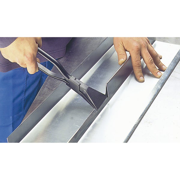 Person mit Blechbiegezange, die ein Metallblech bearbeitet