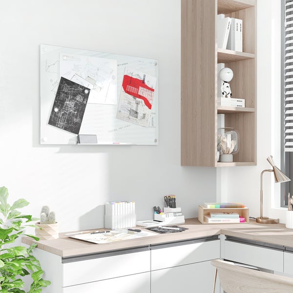 Helles, modernes Büro mit weißer Glas-Magnettafel an der Wand, Holzregal und einem Schreibtisch mit Skizzen, Markern und einer Lampe.