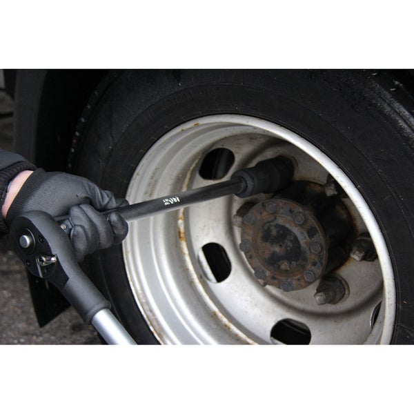 Eine Person benutzt einen Drehmomentschlüssel zum Festziehen der Radmuttern an einem Fahrzeugrad.