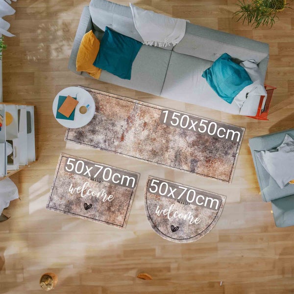 Drei Fußmatten mit den Maßen 150x50 cm und 50x70 cm auf einem Holzboden, eine mit der Aufschrift Willkommen.