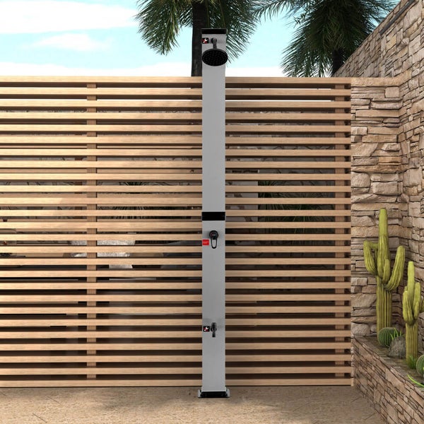Moderne silberne Solardusche in einem hellen Garten mit Holzzaun, Steinwand und Kakteen, ausgestattet mit Duschkopf, Armatur und Fußbrause.