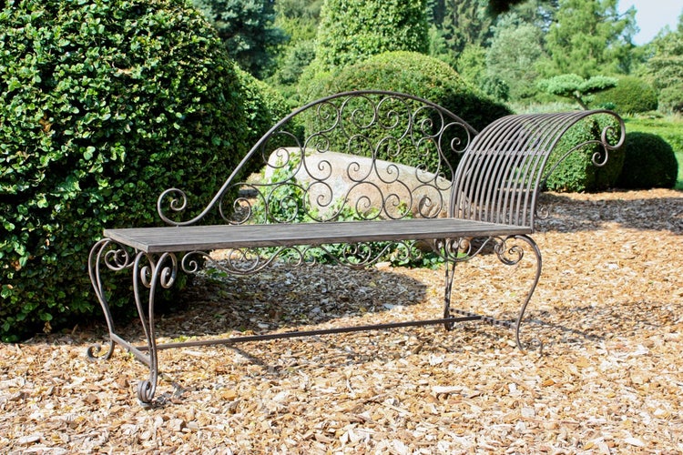 Metall-Gartenbank im Recamiere-Stil mit geschwungener Rückenlehne und Schnörkel-Dekor im Garten auf Rindenmulch.