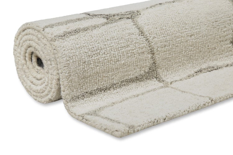 Gerollter Teppich in Beige mit dunklem geometrischem Linienmuster aus gewebtem Textil.