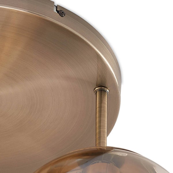 Detailansicht eines runden, messingfarbenen Deckenbaldachins aus gebürstetem Metall mit Verbindungsstab und einer Glaskugel.