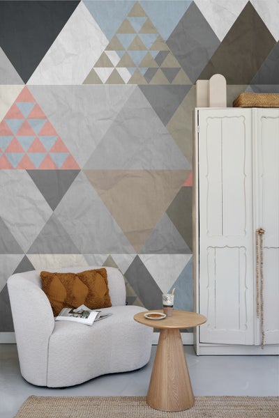 Wohnzimmer mit Sessel, Beistelltisch, Schrank und Tapete mit geometrischen Mustern