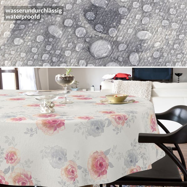 Wasserundurchlässige Tischdecke mit Blumenmuster auf rundem Tisch in hellem Zimmer, Detail zeigt Wassertropfen auf dem Stoff.