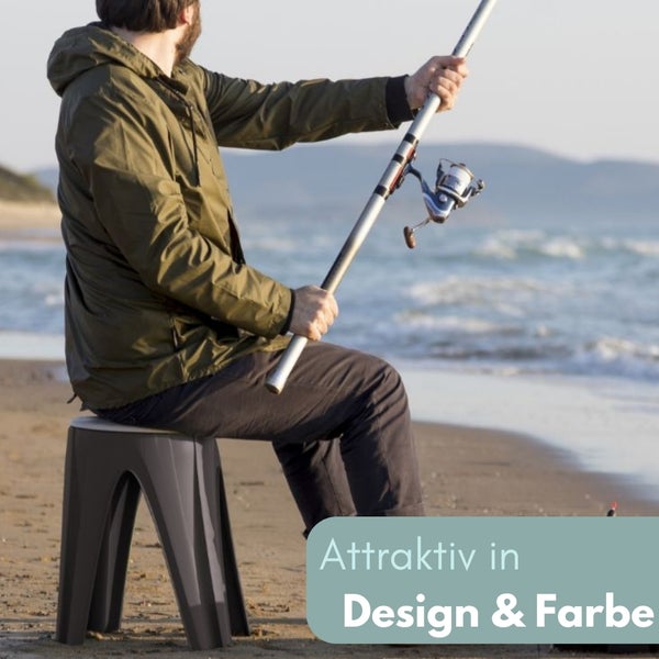 Angler sitzt auf einem Hocker am Strand und hält eine Angelrute.