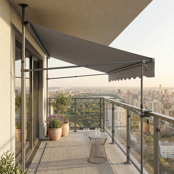 Graue Klemmmarkise auf einem modernen Balkon mit Stadtblick, montiert zwischen Boden und Decke, neben Pflanztöpfen und Beistelltisch.