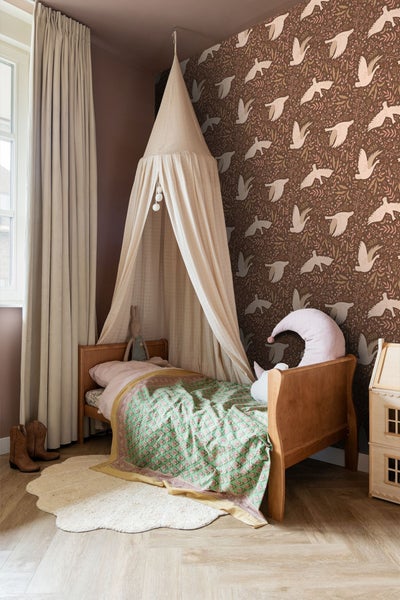 Kinderzimmer mit Himmelbett, gemusterter Tapete und Teppich