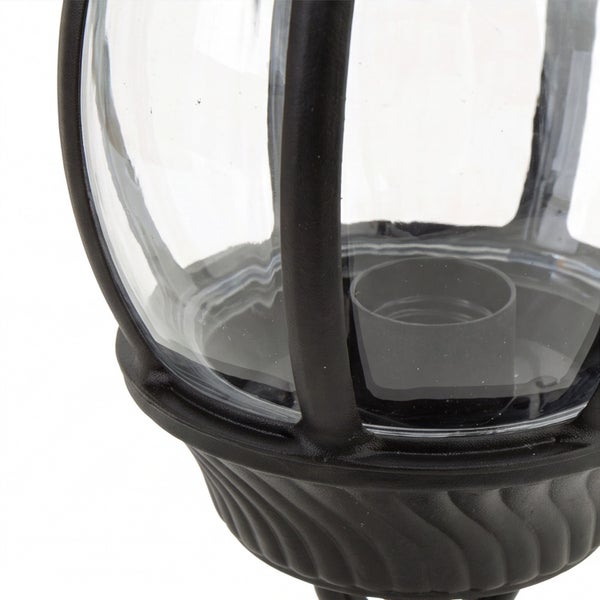 Nahaufnahme einer Außenleuchte mit schwarzem Metallgestell, transparentem Glas und Lampenfassung.