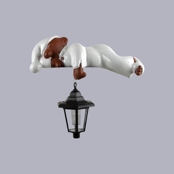 Gartenfigur schlafender Bär in weißem Schlafanzug mit hängender schwarzer Solar-Laterne.