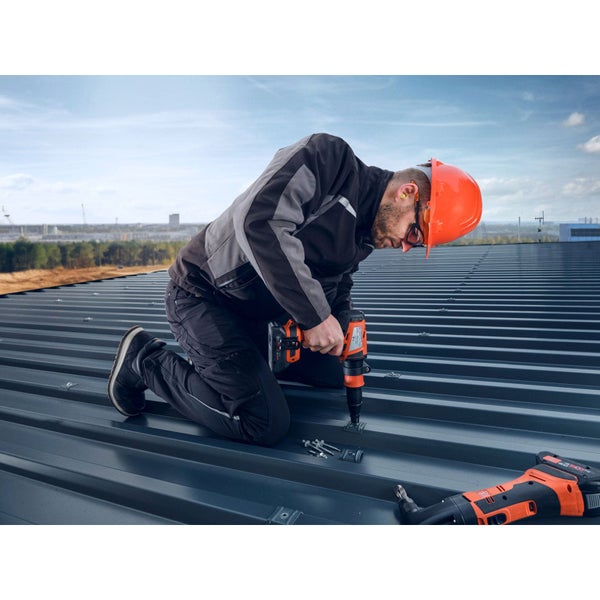 Ein Handwerker befestigt eine Dachplatte mit einem Akku-Blindnietgerät auf einem Dach.