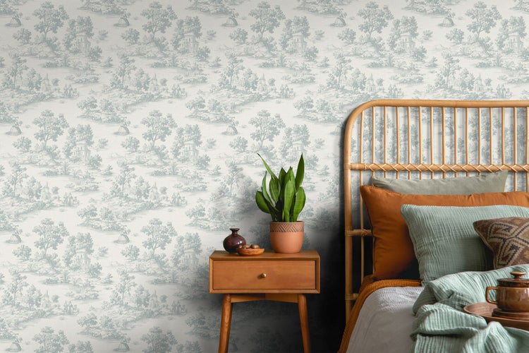 Schlafzimmer mit Toile-de-Jouy-Tapete, Rattankopfteil, Holznachttisch und Bogenhanf.