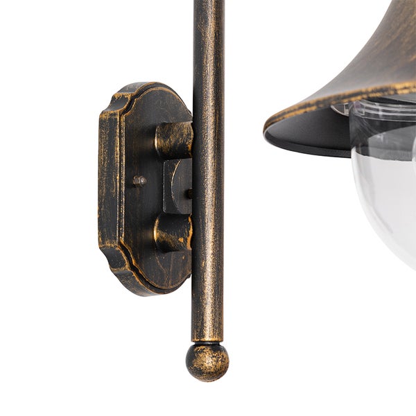 Wandhalterung und Arm einer Wandleuchte im antiken Design aus gold-bronzefarbenem Metall.