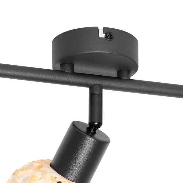 Detailaufnahme einer schwarzen Schienenleuchte mit Lampenschirm aus Rattan