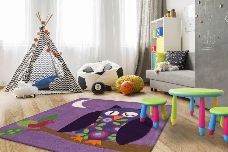 Kinderspielzimmer mit einem rechteckigen Teppich mit Eulenmotiv, Tipi, Sitzsäcken, Kindermöbeln und einer beschreibbaren Wandtafel.