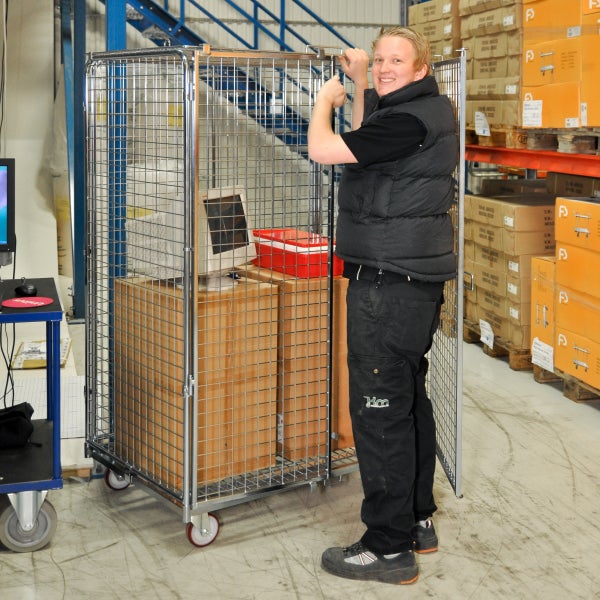 Großer Rollcontainer aus Metallgitter mit Rollen in einem Lager, beladen mit Kartons und einem Monitor, bedient von einem Mitarbeiter.