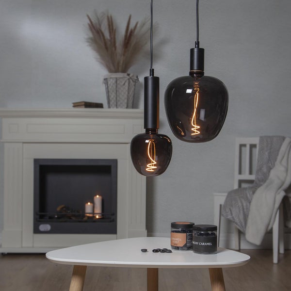 Zwei Pendelleuchten mit dekorativen Leuchtfäden hängen in einem Wohnzimmer über einem Tisch.