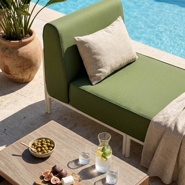 Moderne Gartenlounge in Grün mit weißem Gestell auf einer Terrasse am Pool, dekoriert mit Kissen, Holztisch und Pflanzen.