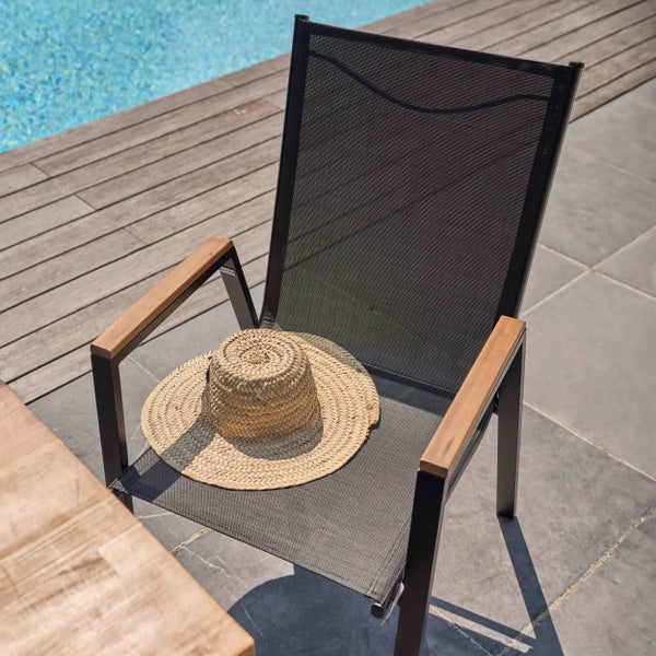 Moderner Gartenstuhl mit dunklem Metallgestell, Netzbespannung und Armlehnen aus Holz auf einer Terrasse am Pool.