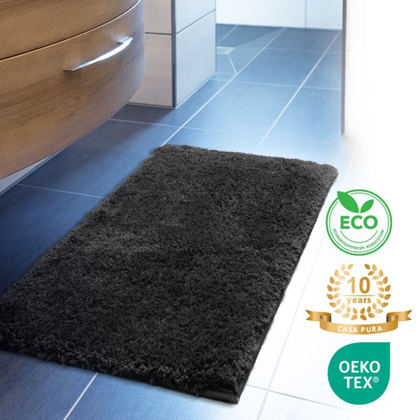 Schwarze Badematte aus Textil vor einem Badezimmerschrank mit den Siegeln ECO, 10 Jahre Casa Pura Garantie und OEKO-TEX