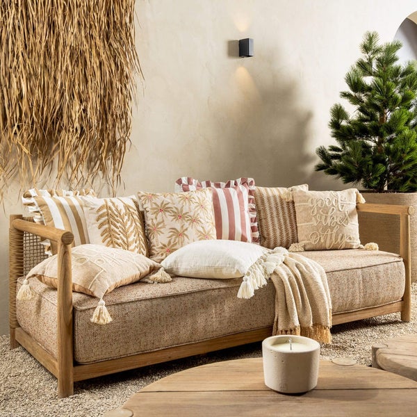 Gemütliche Sitzecke im Außenbereich mit Sofa, Kissen, Decke und Dekoration