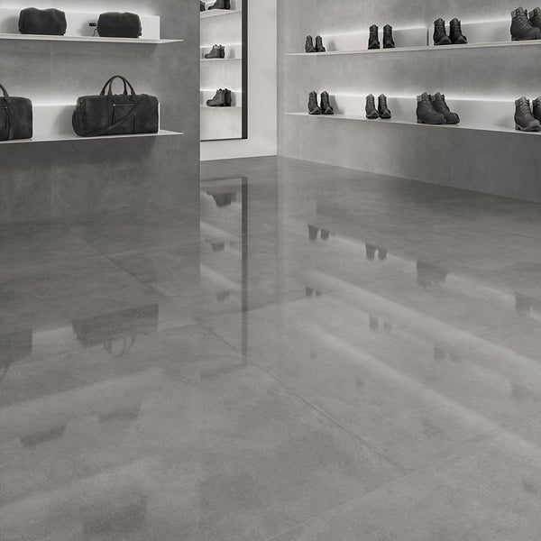Moderne Wand und Bodenfliesen in Betonoptik in einem minimalistisch gestalteten Verkaufsraum mit Regalen und indirekter Beleuchtung.