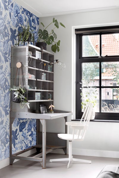Arbeitszimmer mit Metallregal, Schreibtisch, Bürostuhl und Blumentapete