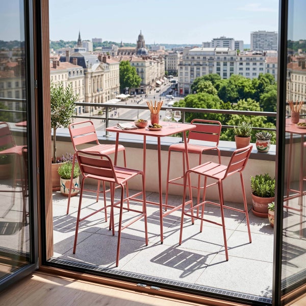 Modernes Balkonset aus Metall mit quadratischem Bartisch und vier Barhockern auf einem hellen Balkon mit Stadtblick.