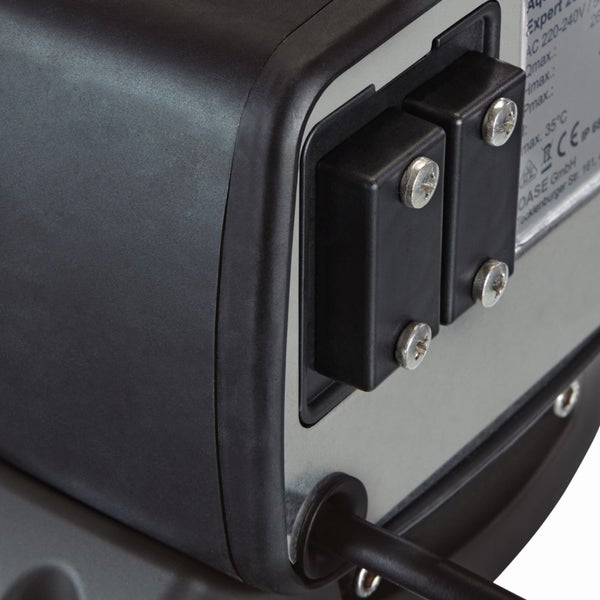 Detailansicht einer Teichpumpe mit verschraubten Abdeckungen für Anschlüsse und einem Kabelauslass auf einer Metallplatte.