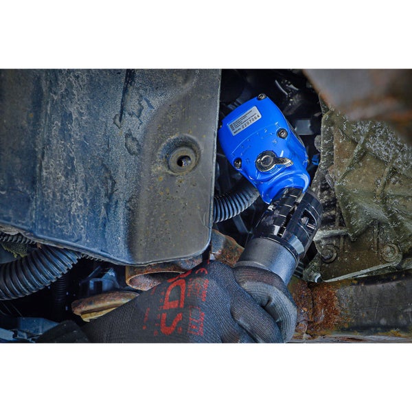 Eine Person benutzt einen pneumatischen Schraubenschlüssel unter einem Auto.