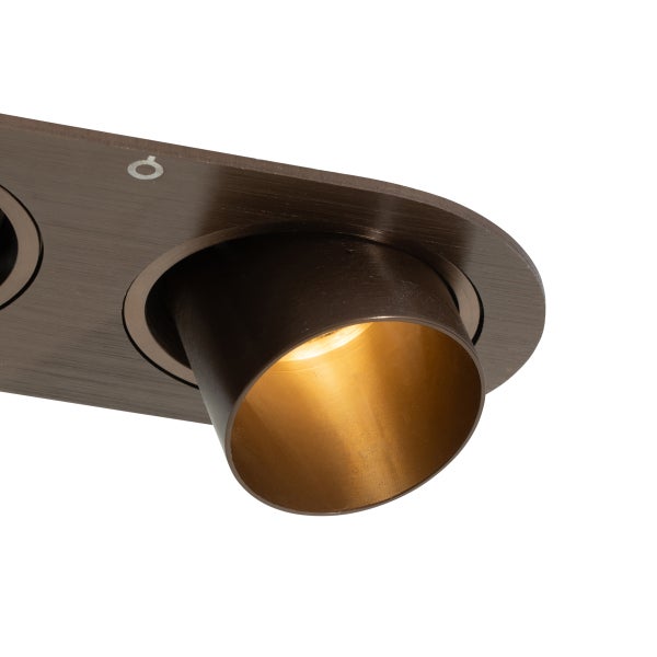 Detailansicht eines verstellbaren Metall-Spots in Bronze-Optik mit warmem Licht.