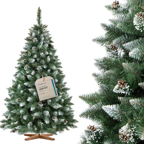 Künstlicher Weihnachtsbaum mit Schnee und Kiefernzapfen auf einem Holzständer mit Vergleichssieger Auszeichnung.
