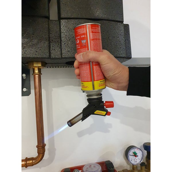 Hand bedient einen Rothenberger Gasbrenner an einem Kupferrohr einer Heizungsinstallation mit Ausdehnungsgefäß und Wasserfilter.