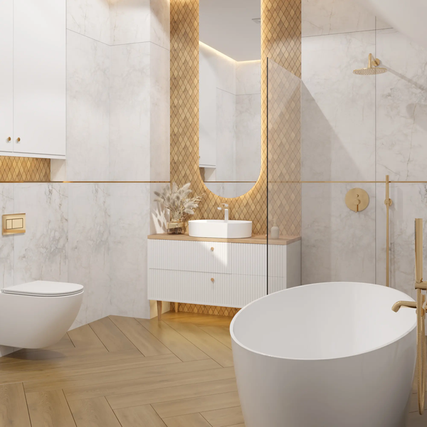 Modernes Badezimmer mit freistehender Badewanne, Wand-WC, Waschtisch mit Aufsatzbecken, Marmor- und Goldfliesen sowie Fischgrätboden.