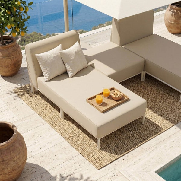 Modernes Lounge-Sofa-Set auf einer hellen Terrasse mit Meerblick, beige Polster, Jute-Teppich, Zitronenbaum und Steinfußboden.