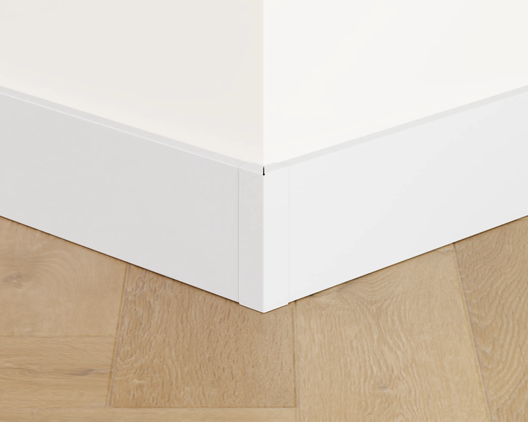 Detailansicht einer weißen Fußleiste an einer Wand und einem Holzboden