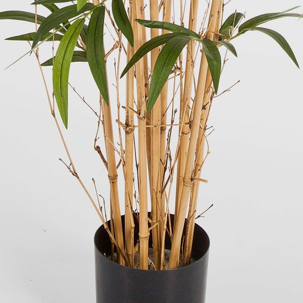 Künstliche Bambuspflanze mit Naturrohren und grünen Blättern in einem schwarzen Topf.