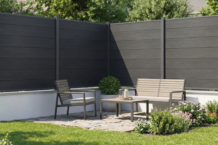 Moderner Garten mit anthrazitfarbenem Sichtschutzzaun aus horizontalen Paneelen, Loungemöbeln auf einer Natursteinterrasse und Bepflanzung.