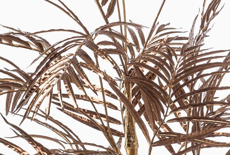 Künstliche Palme mit goldenen Stämmen und bronzefarbenen Blättern in einem schwarzen Topf.