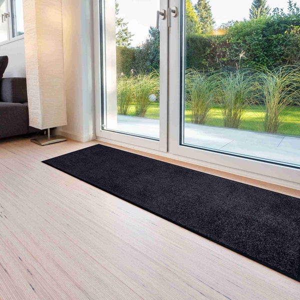 Schwarzer Läufer vor einer Terrassentür auf einem Holzboden.