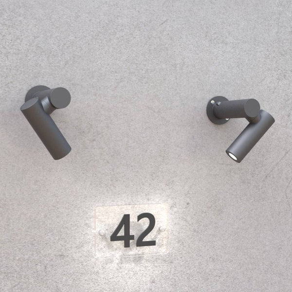 Zwei anthrazitfarbene Außenwandstrahler beleuchten eine Hausnummerntafel mit der Zahl 42 an einer grauen Wand.