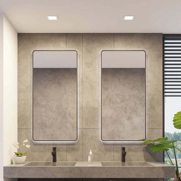 Modernes Badezimmer mit Doppelwaschtisch in Betonoptik, zwei LED-Spiegeln mit abgerundeten Ecken und schwarzen Armaturen.