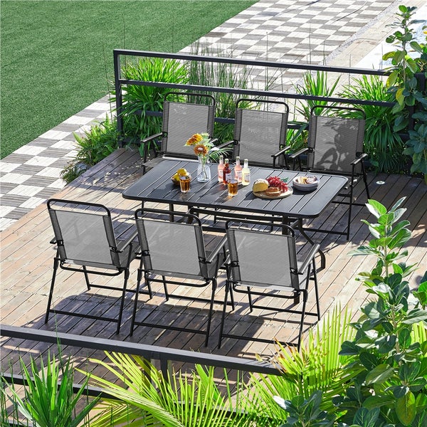 Gartenmöbel-Set mit sechs Klappstühlen und rechteckigem Tisch auf Holzterrasse. Stühle mit Metallgestell und Textilbespannung.